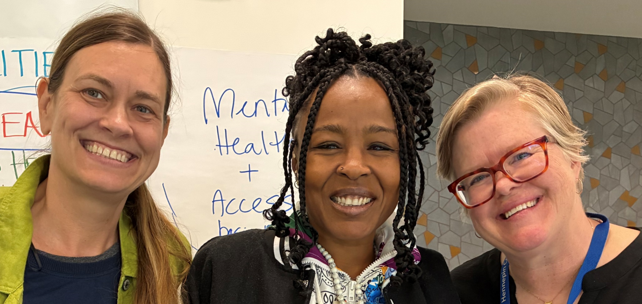 three people standing in front of posters at the community visioning session