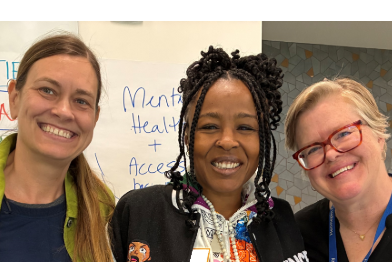 three people standing in front of posters at the community visioning session
