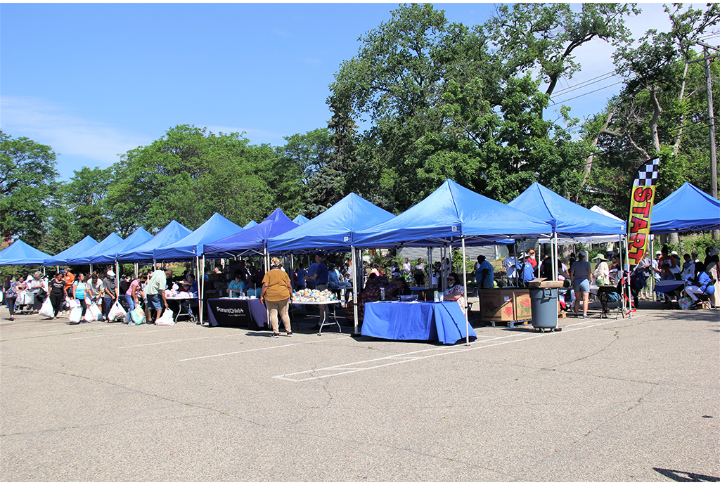 people lining up at tents in a parking lot to get fresh food