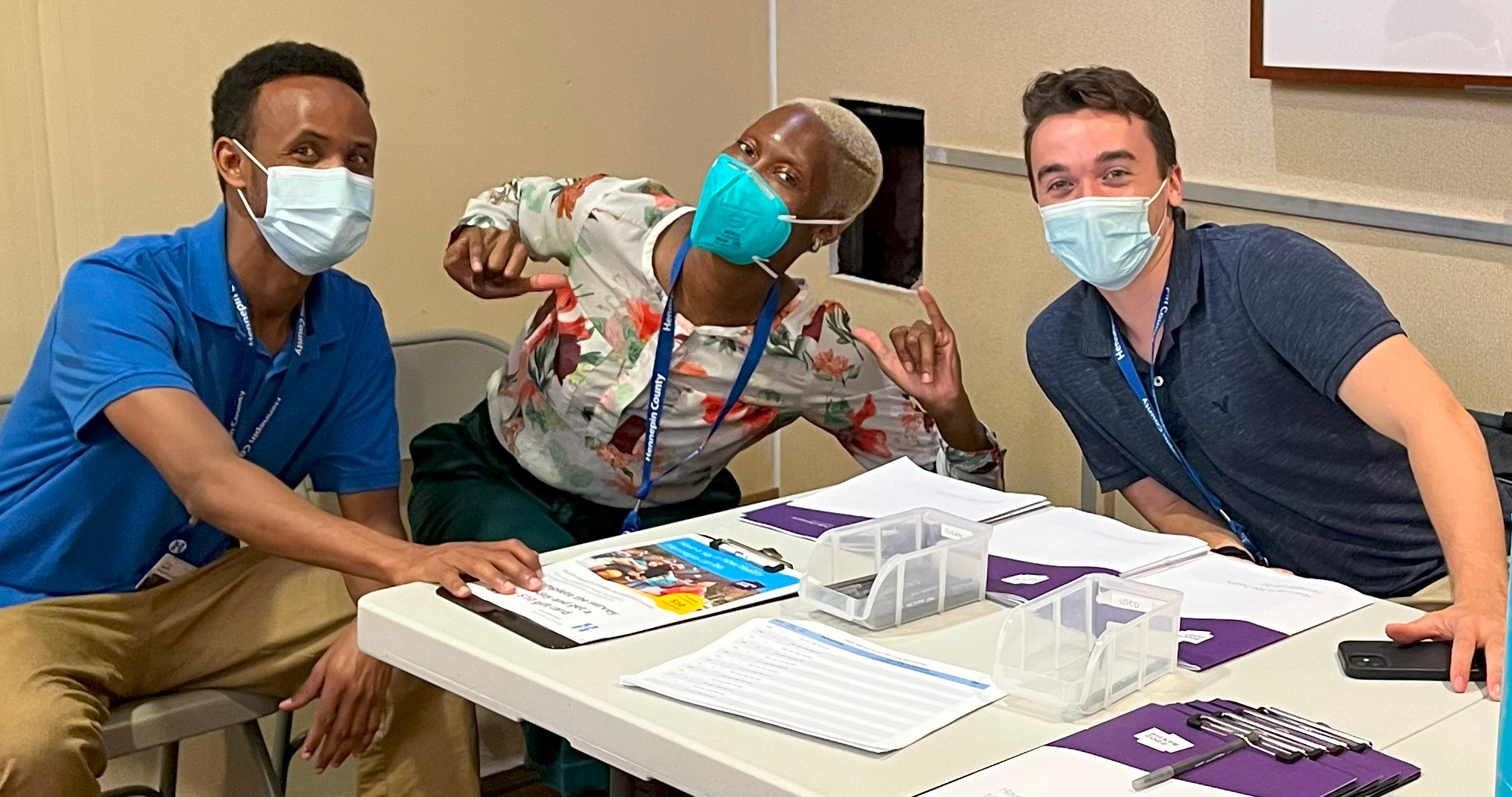 three people wearing masks handing out surveys