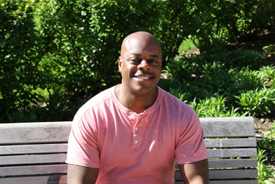 Tryone Patterson, a psychiatric social worker and mental health survivor, sitting on a park bench.