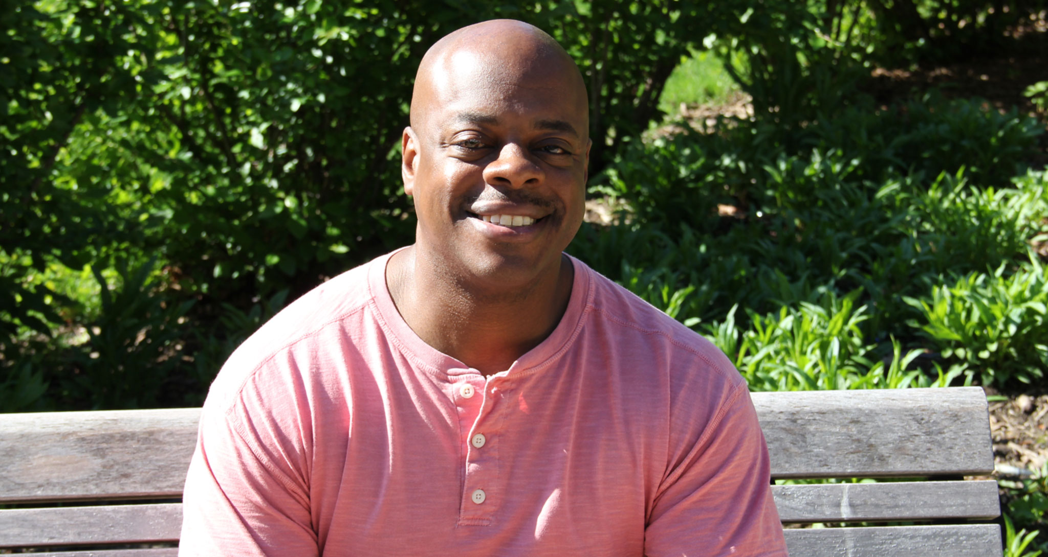 Tryone Patterson, a psychiatric social worker and mental health survivor, sitting on a park bench.
